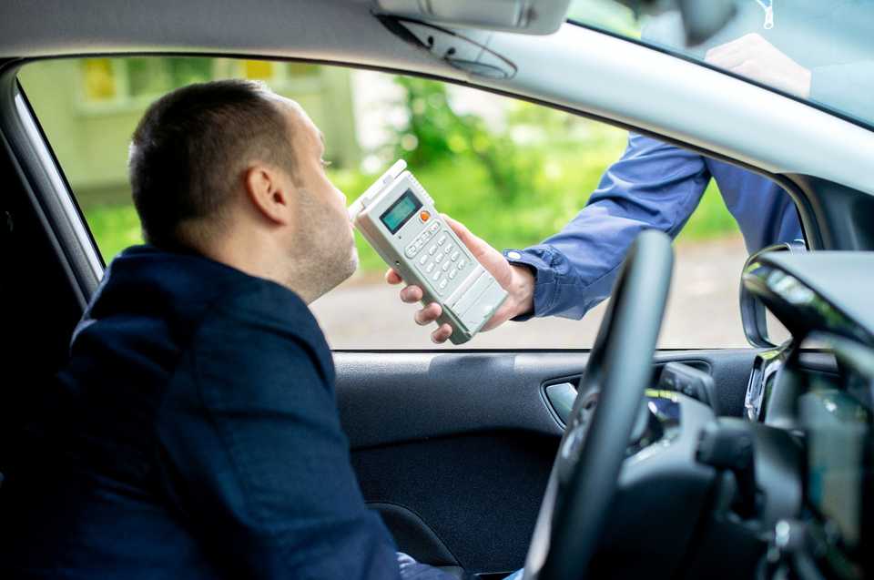 driver being tested for alcohol content with a breathalyzer