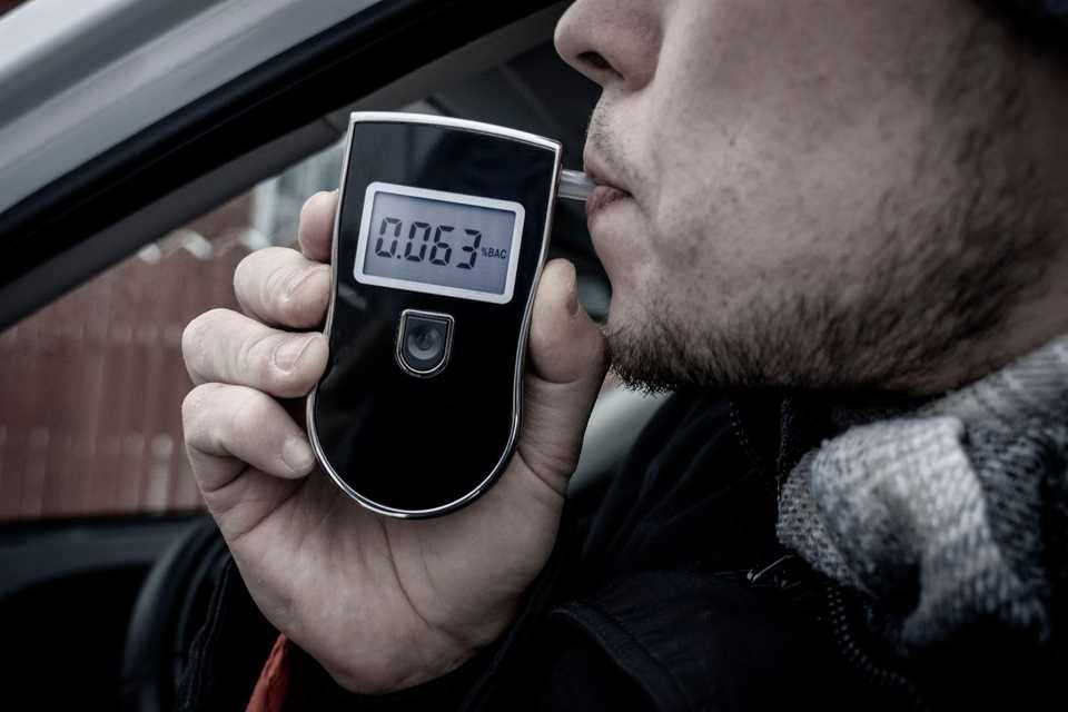 Man with breathalyzer in car